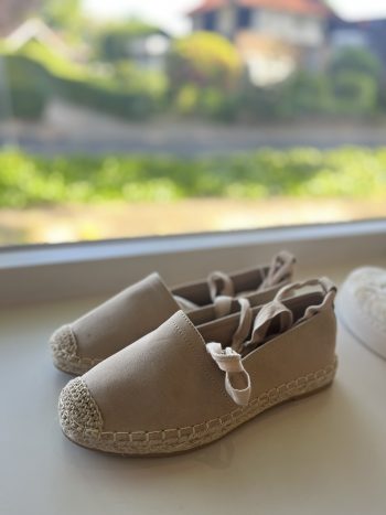 Espradille Sanne zand: beige espadrille met touw-detail op zool, op vensterbank