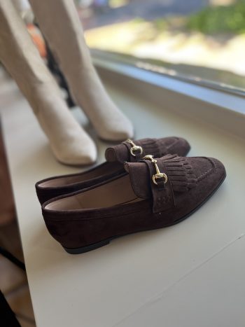 Loafer Geanne bruin gedragen met witte sokken, detail van de goudkleurige sluiting en franjes op het schoeisel