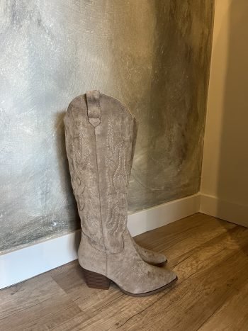 Cowboylaars Paula taupe, suède, staand tegen beige muur op houten vloer