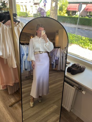 Ballon blouse weddingproof zand, gestegen met witte rok, uitgepast in spiegel in winkelbinnenruimte