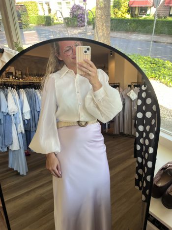 Ballon blouse weddingproof zand, gedragen met witte rok en bruine riem, gefotografeerd in spiegel in winkel