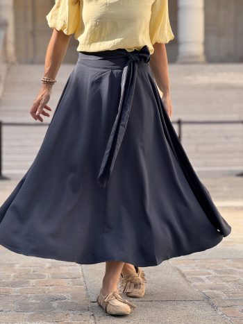 Willeke klokkende rok navy, volledige voorkant, met gele pufmouwen blouse en beige schoenen