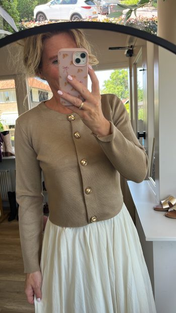 Vestje Madeleine goud in goudkleur met parelmoerkleurige knoppen, gedragen met een crèmekleurige rok