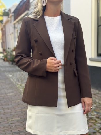 Bruine double-breasted blazer over witte Suedeline rok, gecombineerd met witte top en crèmekleurige riem met goudkleurige ges