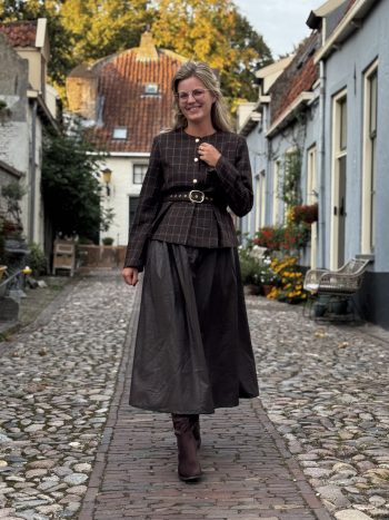 Suedeline rok zwart gedragen met donkergrijze blazer en riem in historisch straatje