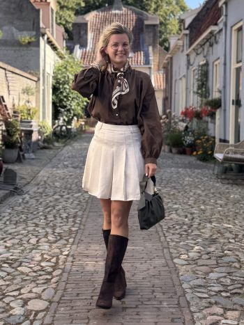 Jessica top navy met witte rok en zwarte laarzen op kasseienstraat